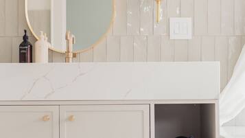 A bathroom with a white vanity, a gold-framed mirror, a towel shelf, and a toilet.