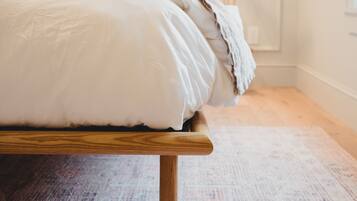 A bed with a wooden frame and white bedding in a room with a patterned carpet.