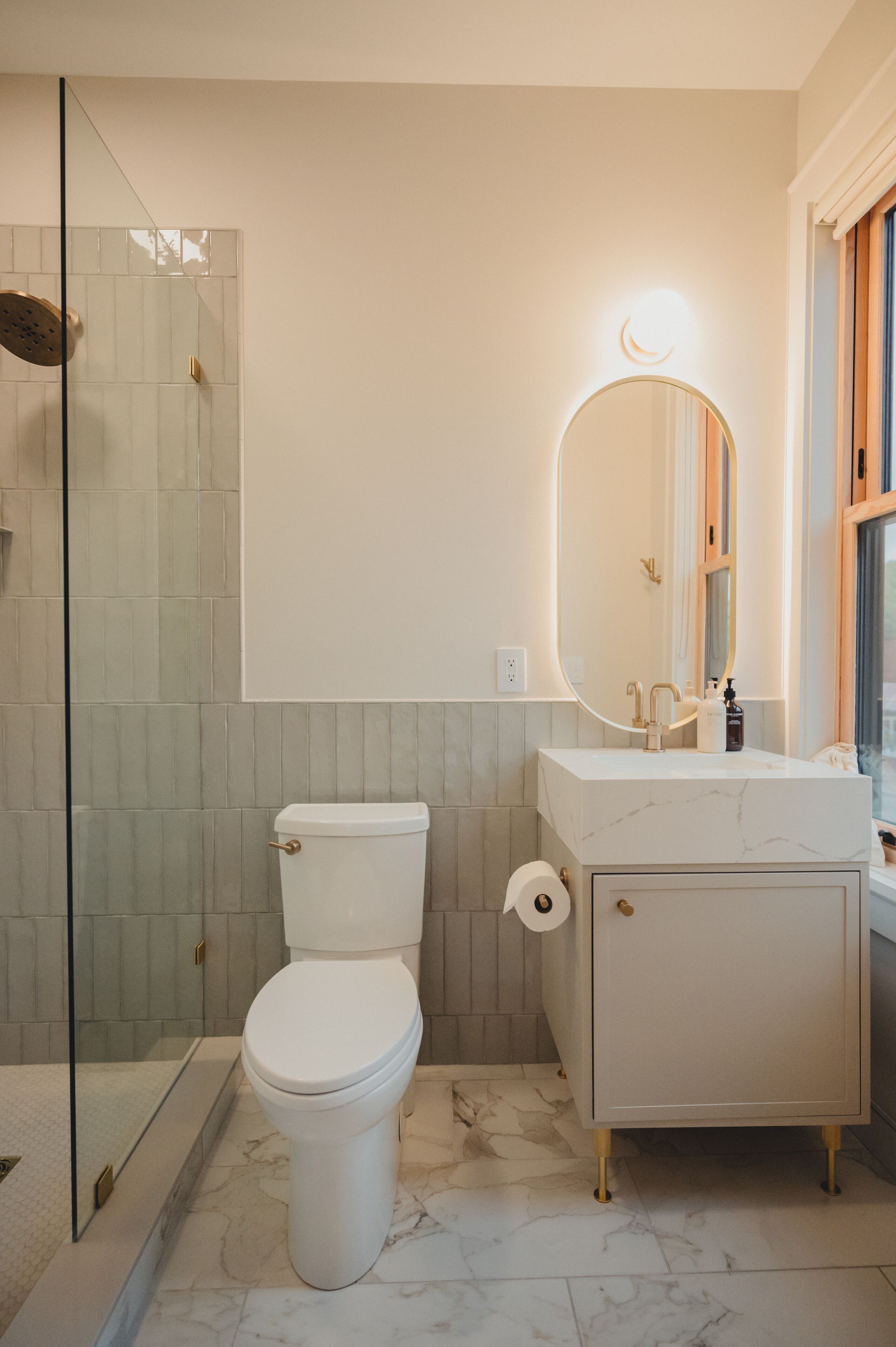 A bathroom with a toilet, a sink, a mirror, and a shower area.