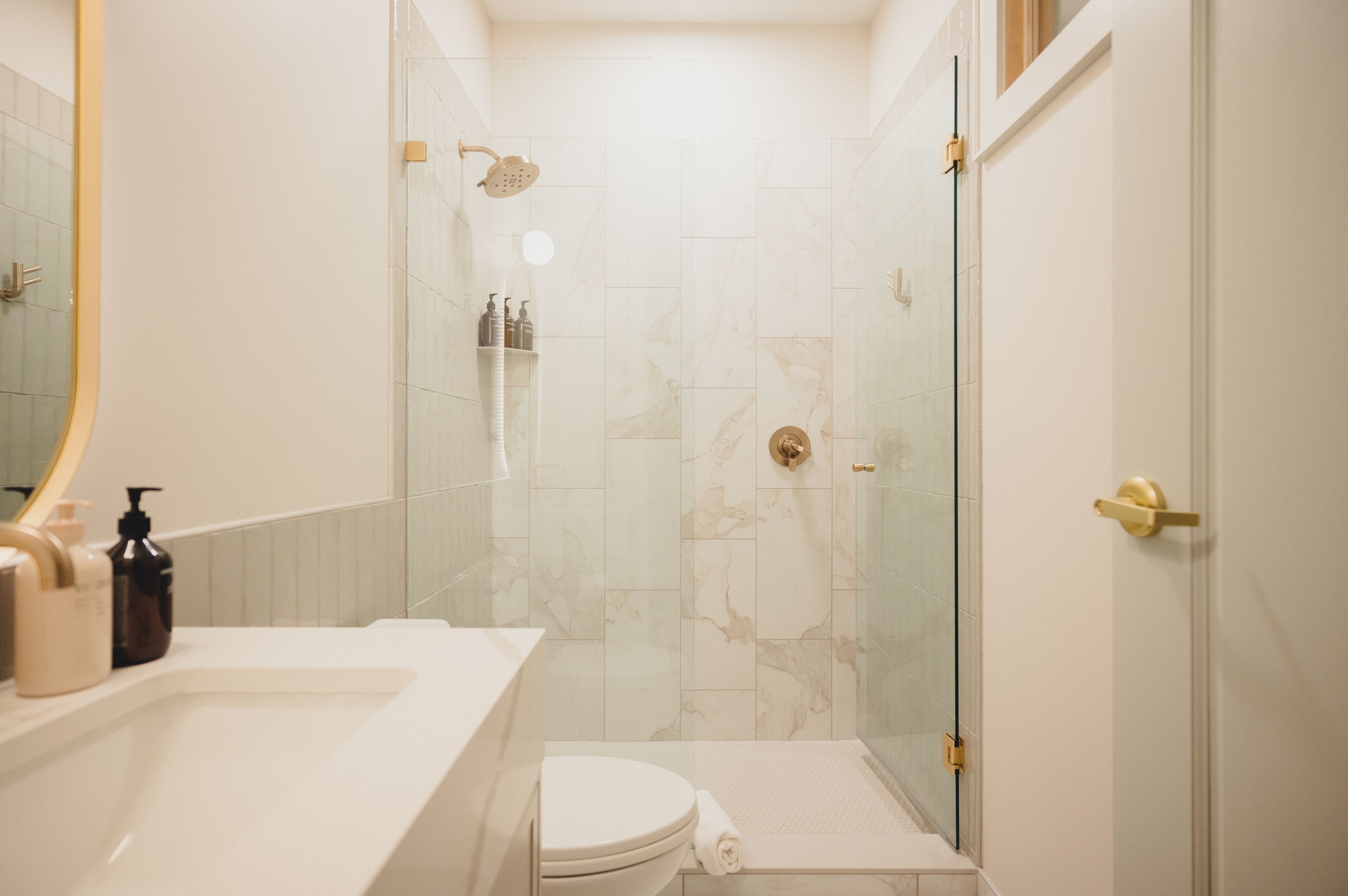 A modern bathroom with a glass-enclosed shower, a white sink, and a toilet.