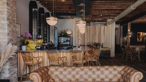 A bar area with a leather couch, wicker chairs, and a bar counter. - St. James Social (Bayfield)