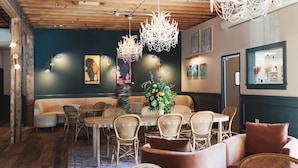 A dining area with a wooden ceiling, wicker furniture, and a central floral arrangement. - St. James Social (Bayfield)