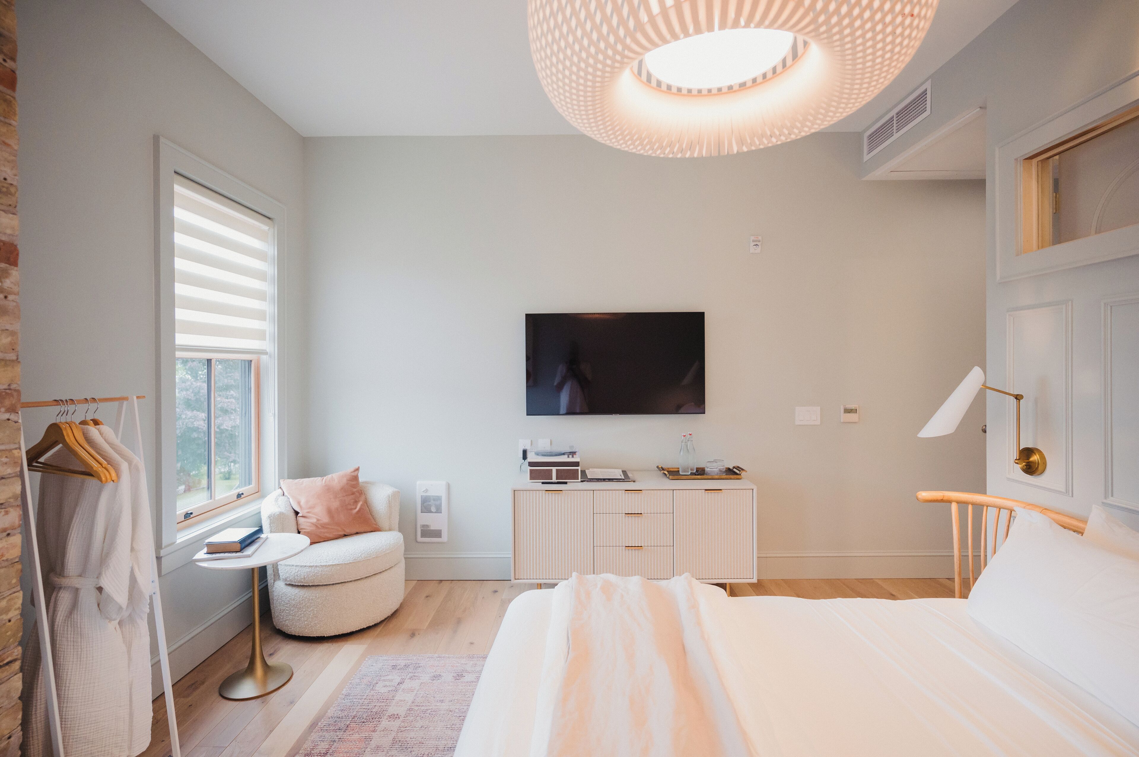 A modern bedroom with a bed, bedside table, and a TV mounted on the wall.