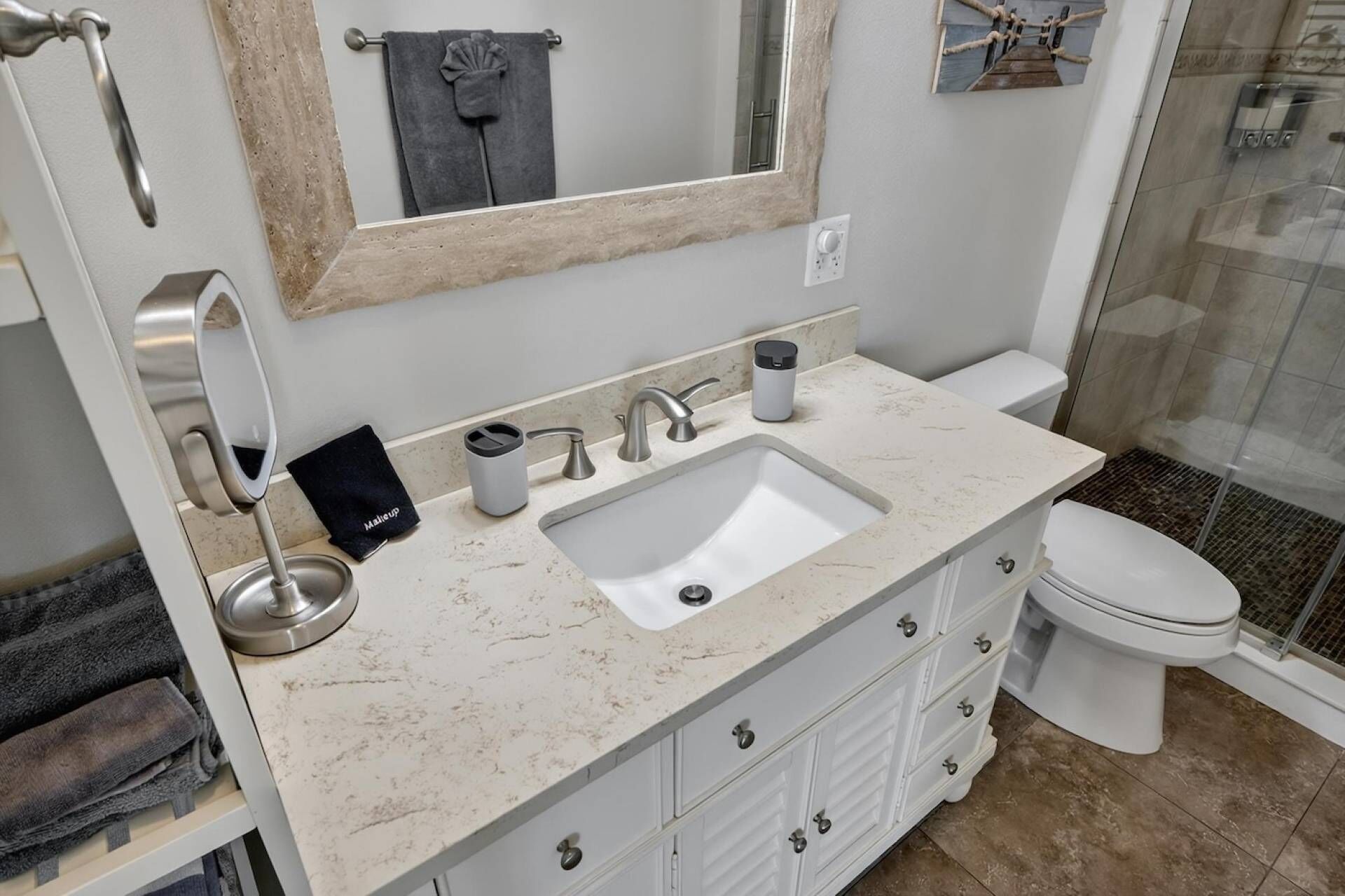 Une salle de bain comprenant un lavabo, un miroir, un porte-serviettes, des toilettes et un espace douche.