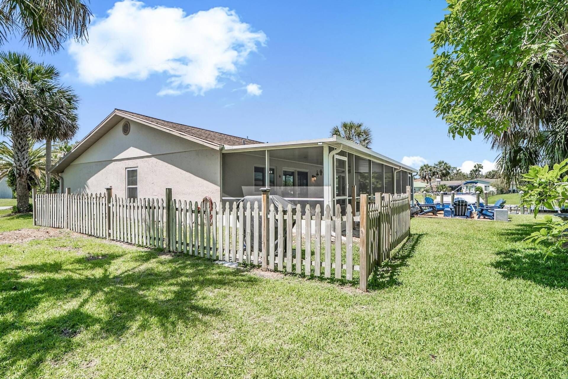 A single-story house with a screened porch, a fenced yard, and a pool area with lounge chairs.