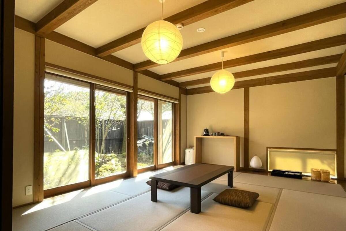 A tatami mat room with a low table, sliding doors, and a view of the outdoors.