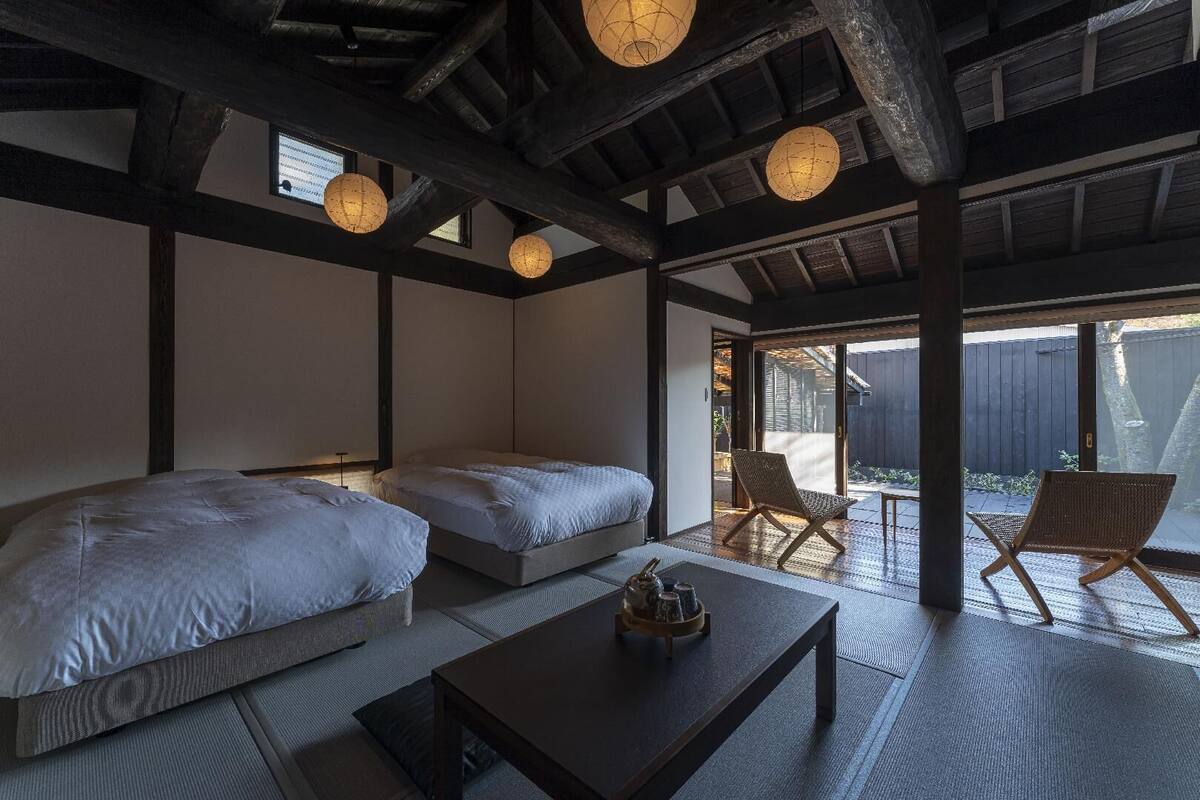 A room with two beds, a table, and a chair.