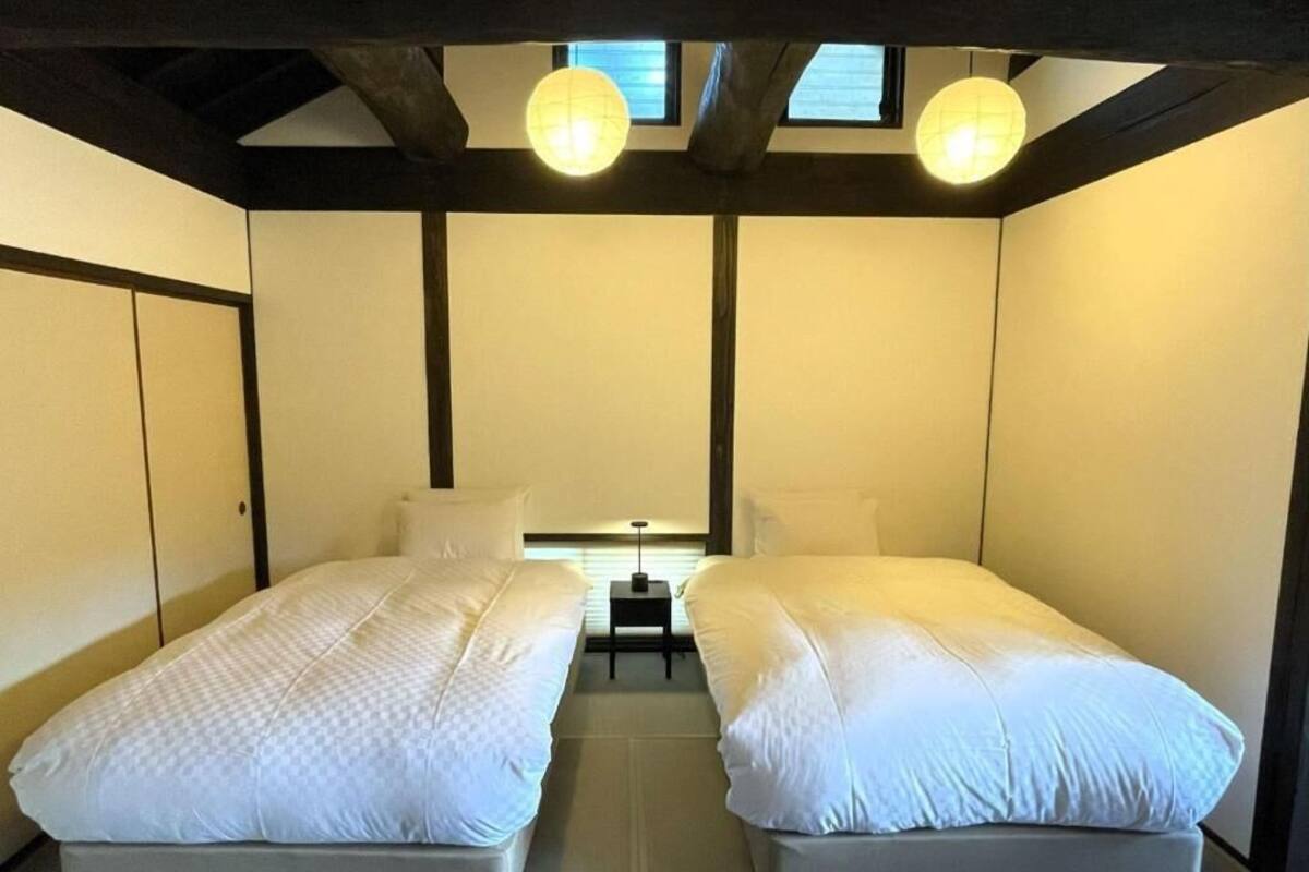 A room with two beds, a small table, and a lamp.