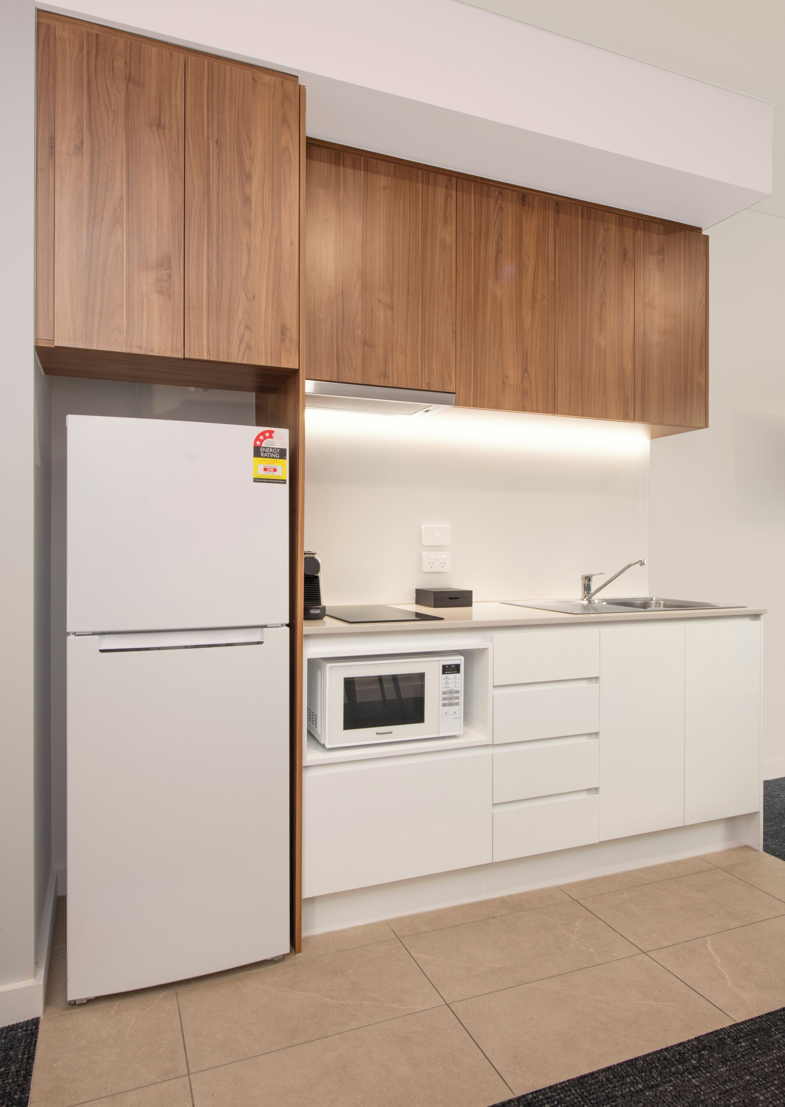 A modern kitchen with white cabinetry, a built-in microwave, and a stainless steel sink.