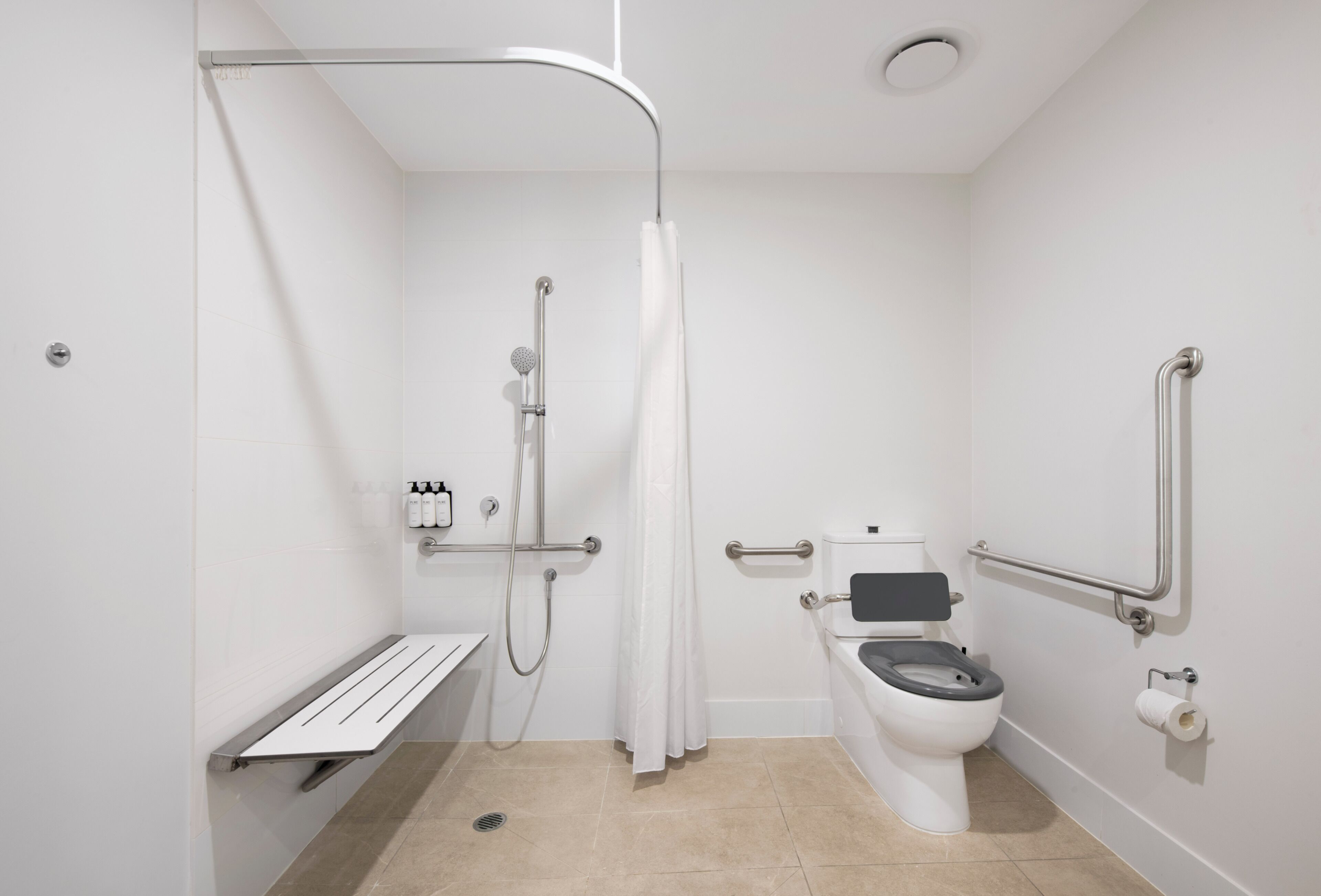 A modern bathroom with a shower, toilet, and grab bars.