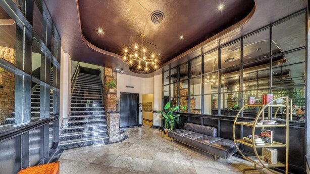 A spacious lobby with a staircase, a seating area, and a bookshelf. - Against the Riverwalk/King (San Antonio)