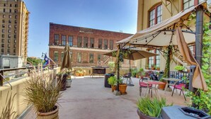 A rooftop patio with outdoor seating, potted plants, and a view of a brick building. - Against the Riverwalk/King (San Antonio)