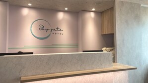 A reception desk at Skygate Hotel with a marble top and a wooden accent. - Sky Gate Hotel (Taipei)