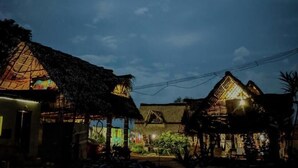 A traditional village with thatched-roof houses and a small market area. - Time Travellers Hostel (Tindivanam)