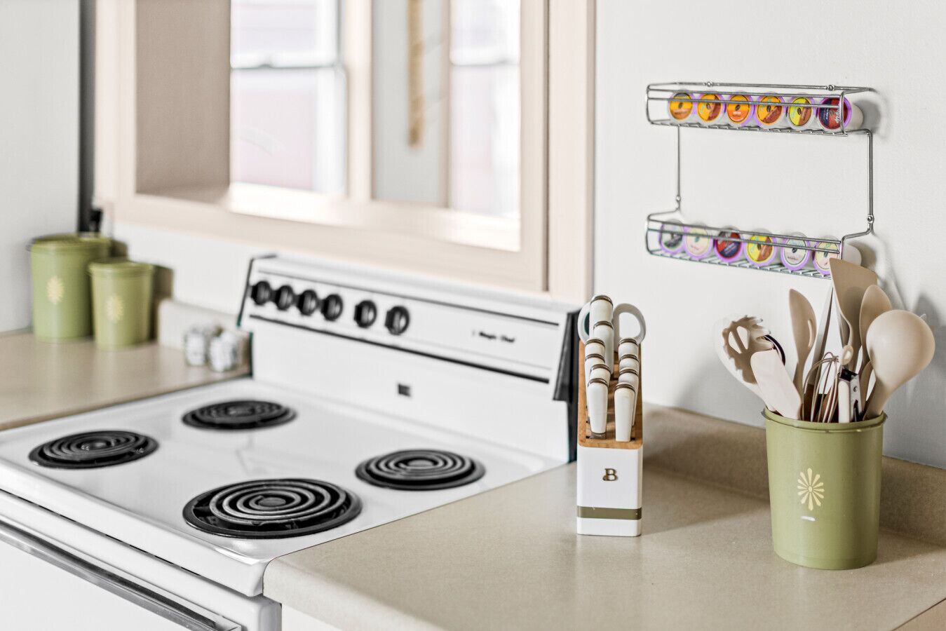 A kitchen with a stove, a spice rack, and a utensil holder.