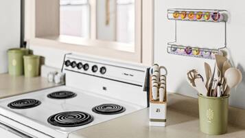 A kitchen with a stove, a spice rack, and a utensil holder.
