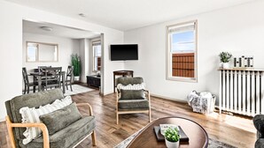 A modern living room with a fireplace, a dining area, and a TV mounted on the wall. - Superior Stay Very Cozy + Minutes to Duluth/Lake (Superior)