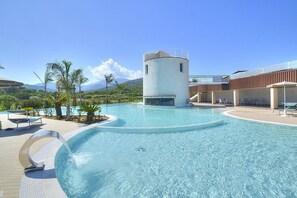 A swimming pool with a circular water feature, lounge chairs, and a building with a cylindrical tower. - Casa Ondina A: A welcoming apartment situated in a quiet location, a few minutes from the town center, with Free WI-FI. (Casal Velino)