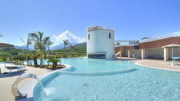 A swimming pool with a circular water feature, lounge chairs, and a building with a cylindrical tower. - Casa Ondina B: A welcoming apartment situated in a quiet location, a few minutes from the town center, with Free WI-FI. (Casal Velino)