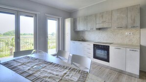 A modern kitchen with white cabinets, a built-in oven, and a large window overlooking a balcony. - Casa Ondina B: A welcoming apartment situated in a quiet location, a few minutes from the town center, with Free WI-FI. (Casal Velino)