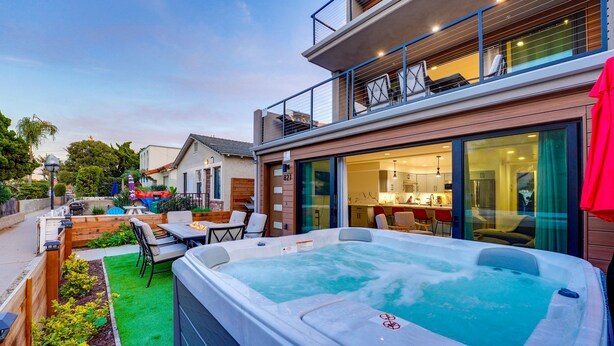 Een modern huis met een jacuzzi, buiten zitplaatsen en een groot raam met uitzicht op de achtertuin.