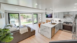 Een moderne keuken met een marmeren eiland, roestvrijstalen apparatuur en een eetgedeelte met een groot raam.