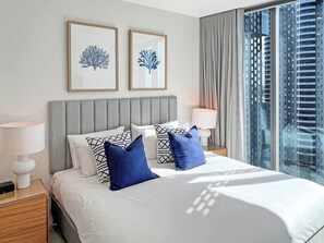 A modern hotel room with a large bed, grey headboard, and two framed artworks on the wall. - Luxury Signature Stay Ocean Views 2BR Lvl14 (Broadbeach)