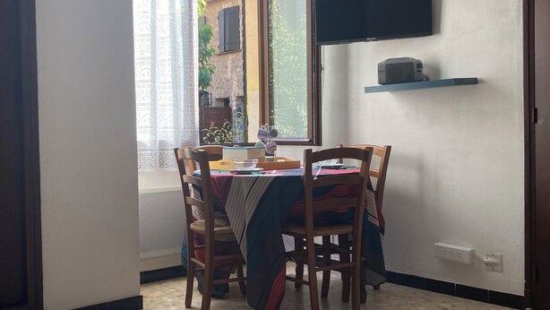 Ett litet matområde med ett bord och stolar, en tv som är monterad på väggen och en luftkonditioneringsanläggning ovanför bordet.
