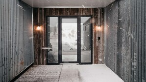 Ein moderner Korridor mit einer Holzwand, einer Glastür und einer Metallwand.