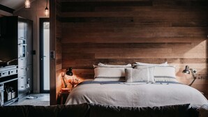 Une chambre à coucher avec une tête de lit en bois, un lit avec une literie blanche, une table de chevet avec une lampe et une commode avec des tiroirs.