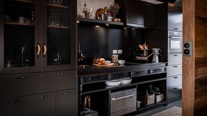 Une cuisine moderne avec des meubles de couleur sombre, des appareils en acier inoxydable et une variété d’ustensiles de cuisine et d’accessoires.