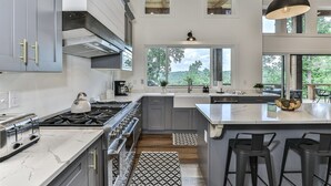A modern kitchen with a large island, stainless steel appliances, and a view of the outdoors. - The Cabin On Faraday | Ellijay, GA (Ellijay)