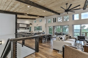 Un amplio salón con cocina, comedor y una escalera que conduce a la planta superior.