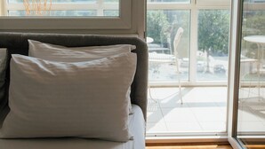 Un dormitorio con un ventanal grande, una cama con ropa de cama blanca y vistas a la ciudad.