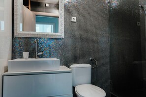 A bathroom with a white sink, mirror, and toilet.