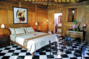 Classic hotel room with a large bed, wooden headboard, and checkered floor.