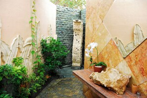 Escape to a serene oasis with lush greenery, traditional carvings, and a peaceful bench.