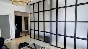 Quarto de hotel com uma grande janela, um candelabro, uma cama e uma escrivaninha.