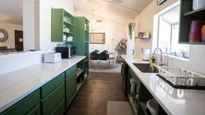 Una cocina moderna con armarios verdes, una encimera blanca y un comedor con mesa y sillas.