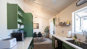 Una cocina compacta con comedor, armarios verdes, microondas y ventana.