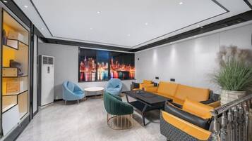A modern living room with a cityscape view, a sofa, chairs, and a coffee table.