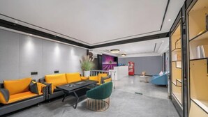 Un hall d’entrée moderne avec un canapé, une table basse et des fauteuils. On y trouve un comptoir d’accueil et une plante en arrière-plan.