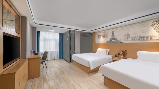 Une chambre d’hôtel avec deux lits, un bureau, une télévision et une fresque représentant des monuments parisiens.