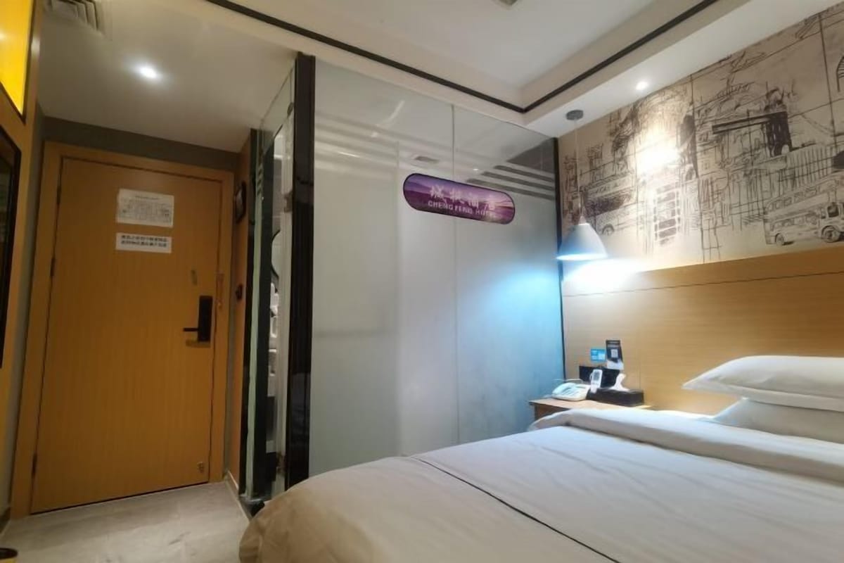 A hotel room with a bed, a nightstand with a phone, and a wall with a cityscape mural.