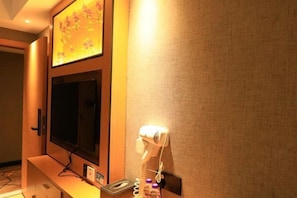 A hotel room with a flat-screen TV mounted on the wall, a hairdryer, and a small table with a bottle and a tissue box. - Yinuo Hotel (Guangzhou Chenjiaci Caihongqiao Metro Station) (Guangzhou)