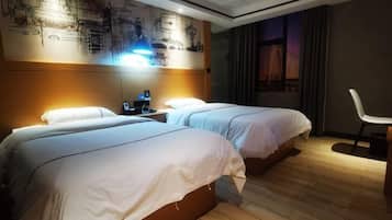 A hotel room with two beds, a nightstand, a desk, and a chair.