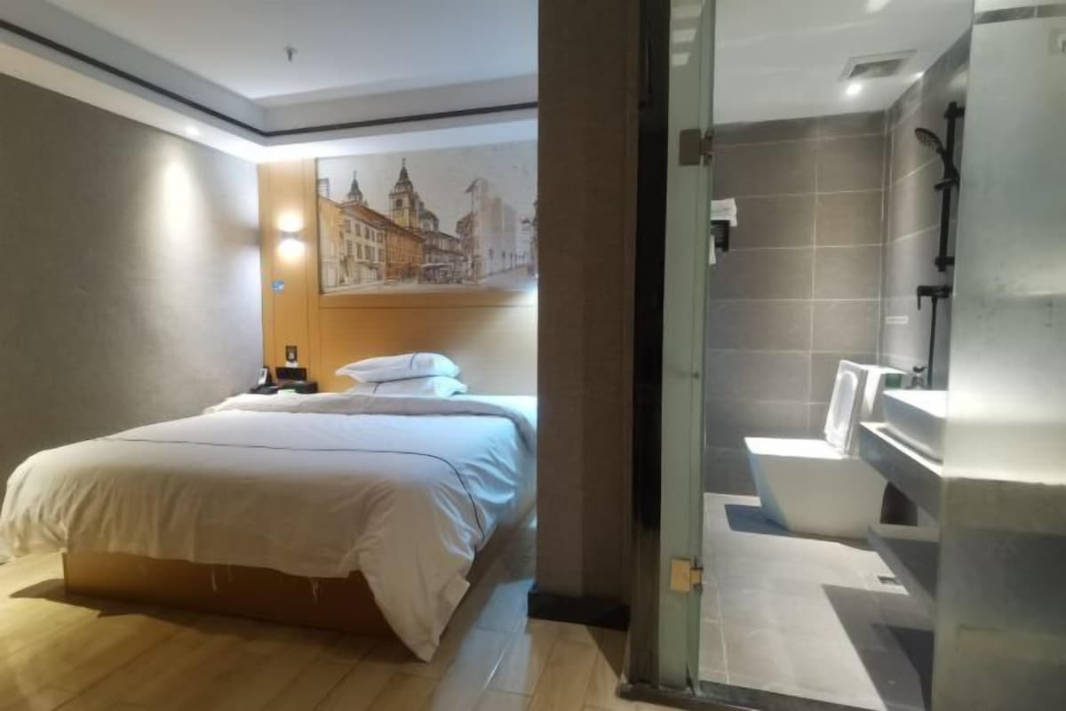 A hotel room with a bed, a bathroom with a bathtub, and a glass shower enclosure.