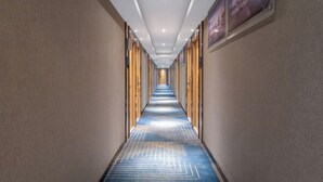 Un long couloir étroit, avec un tapis à motifs, des lambris en bois sur les murs et des luminaires au plafond.