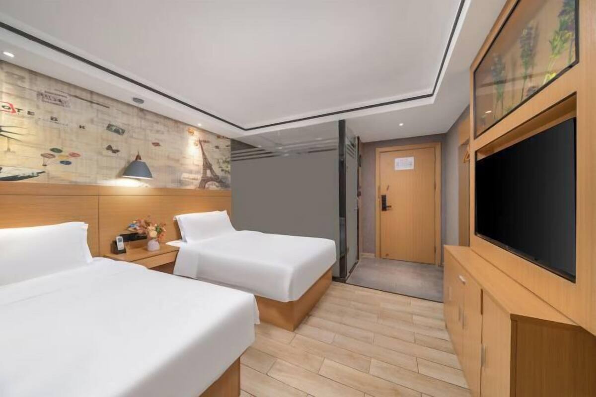 A hotel room with two beds, a television, a wooden cabinet, and a wall with a mural.