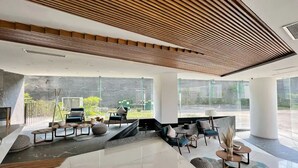 Eine moderne Lobby mit Holzboden, großen Fenstern und einer Sitzecke mit Sofas und Tischen.